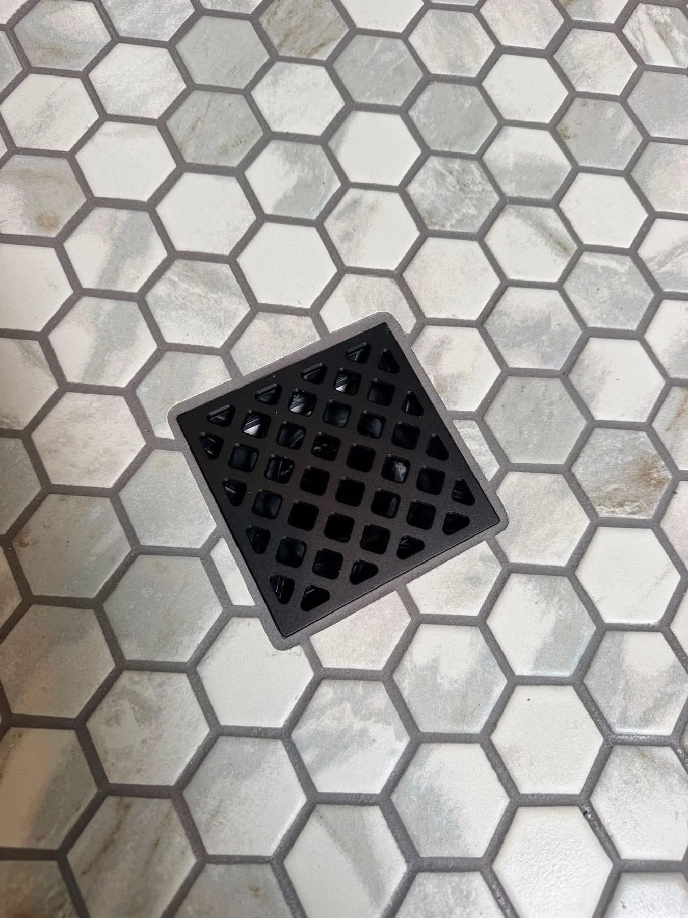 Hexagonal mosaic shower floor around a square drain