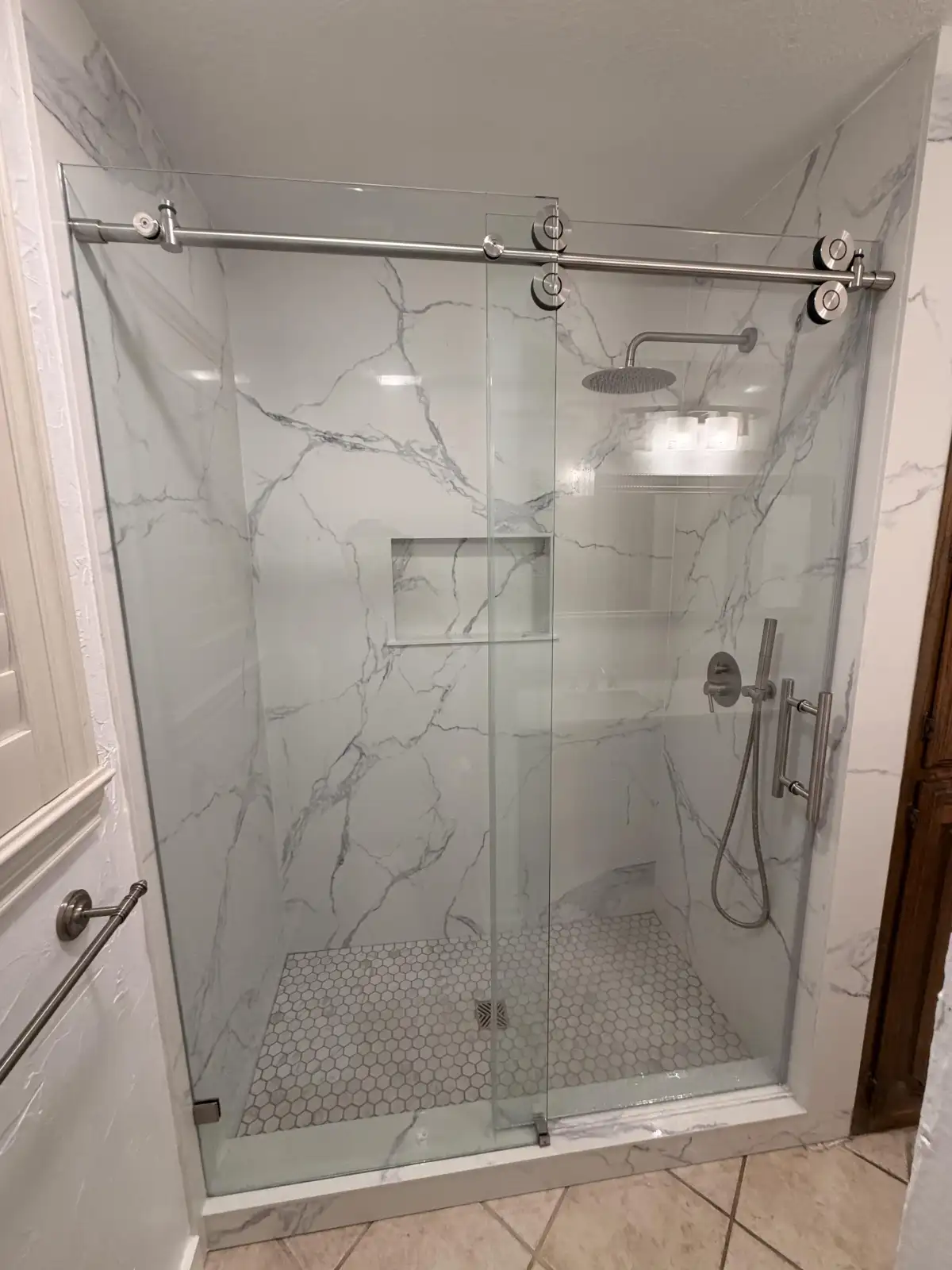 Marble walk-in shower with sliding glass door and rain shower head